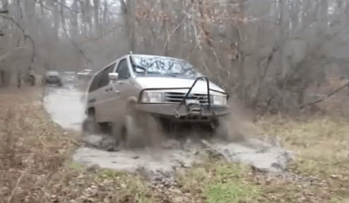A Van Is Driving Through A Muddy Area With Trees In The Background GIF
