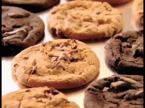 A Variety Of Cookies Are On A Table Including Peanut Butter And Chocolate Chip Cookies GIF