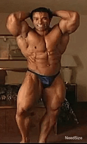 A Very Muscular Man In A Blue Thong Is Standing In A Room . GIF
