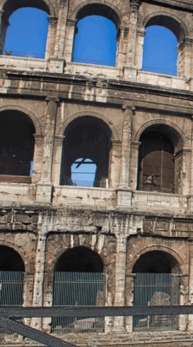 A Very Old Building With Arches And A Blue Sky Behind It GIF