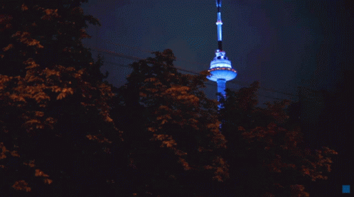 A Very Tall Tower Is Lit Up With Blue Lights GIF