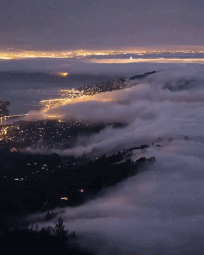 A View Of A City At Night With A Lot Of Clouds GIF