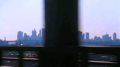 A View Of A City Skyline Through A Fence GIF