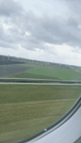 A View Of A Field From An Airplane Window With A Cloudy Sky GIF