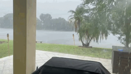 A View Of A Lake From A Porch During A Rainy Day GIF