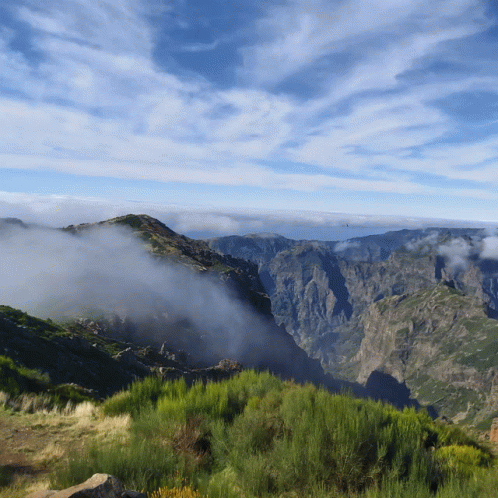 A View Of A Mountain Range With A Blue Sky And Clouds In The Background GIF