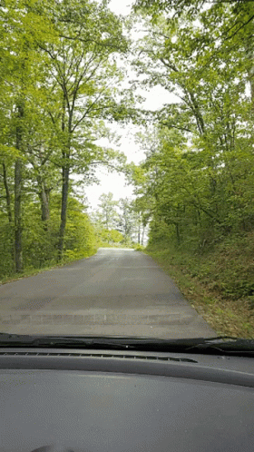 A View Of A Road Through A Car Windshield GIF