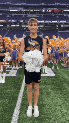 A Vikings Cheerleader Is Holding A Bunch Of Pom Poms On A Field GIF