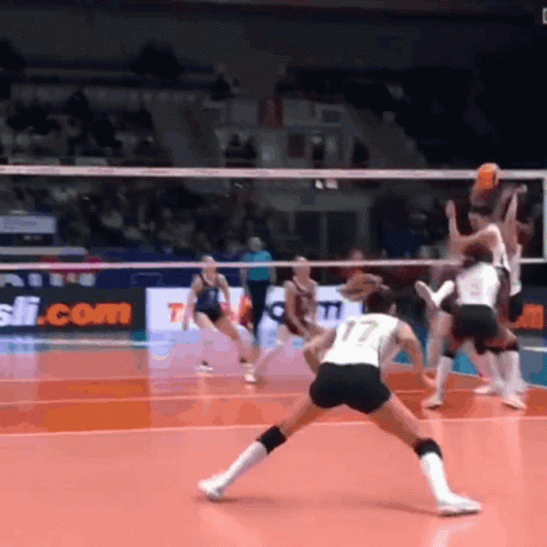 A Volleyball Game Is Being Played In Front Of A Sign That Says ' T.com ' GIF