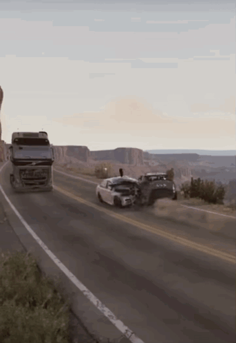 A Volvo Truck Is Driving Down The Road Next To A Car GIF
