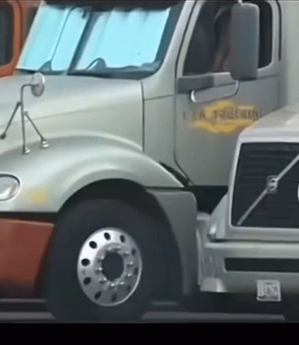 A Volvo Truck Is Parked Next To A Silver Truck GIF