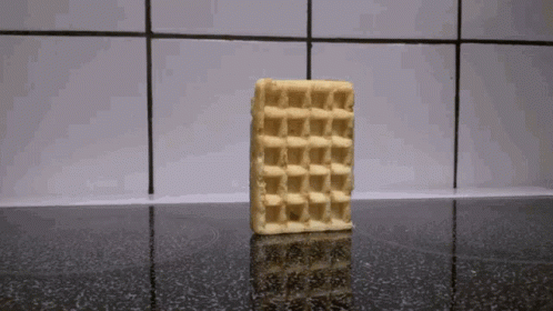 A Waffle Is Sitting On A Stove Top With A Tiled Wall In The Background GIF