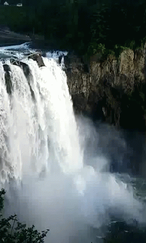 A Waterfall Is Surrounded By Trees And A Cliff GIF