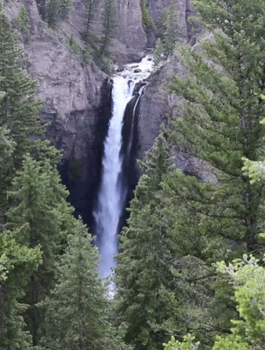 A Waterfall Is Surrounded By Trees And Cliffs GIF