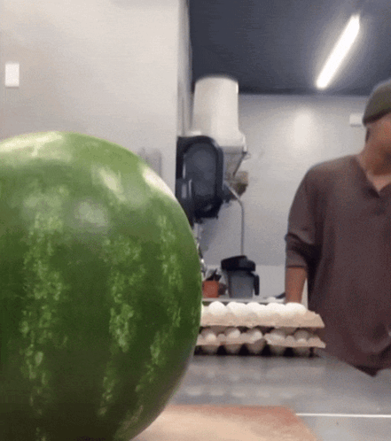 A Watermelon Sits On A Counter Next To A Man GIF