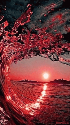 A Wave Is Breaking In The Ocean At Sunset And The Sun Is Reflected In The Water GIF