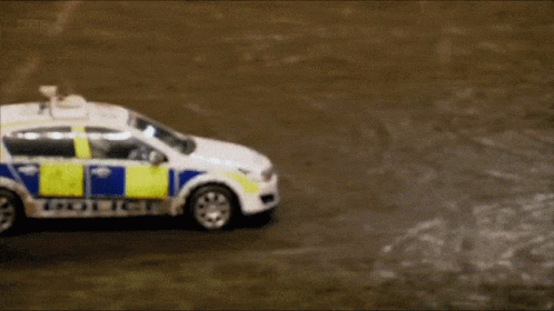 A White And Blue Police Car Is Driving Down A Road GIF