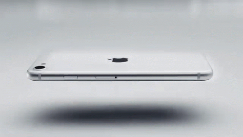 A White Apple Iphone Is Floating On A White Surface . GIF