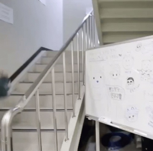 A White Board With Drawings On It Is Next To A Railing And Stairs GIF
