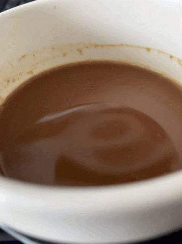 A White Bowl Filled With Brown Liquid With A Swirl In It GIF