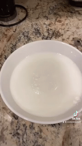 A White Bowl Filled With Water Is On A Counter Top . GIF