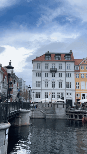 A White Building With A Red Roof Sits Next To A River GIF