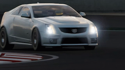 A White Cadillac Is Driving On A Track With Its Headlights On GIF