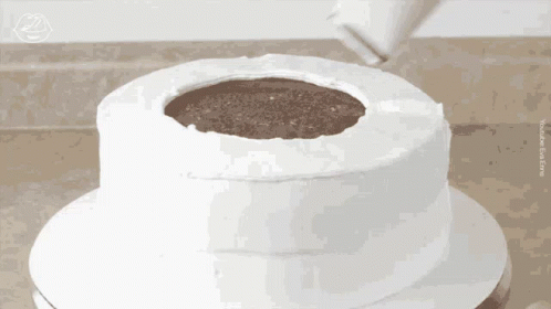 A White Cake With A Hole In The Middle Is Being Frosted GIF