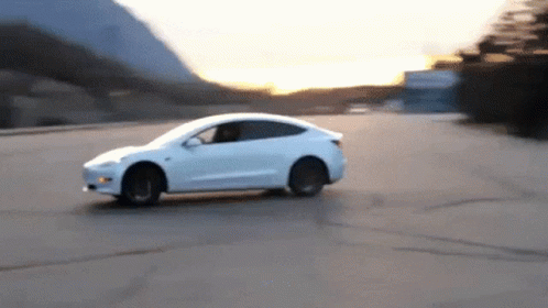 A White Car Driving Down A Road With Mountains In The Background GIF