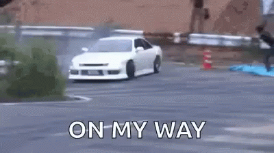 A White Car Is Drifting On A Road With The Words `` On My Way '' Written On The Bottom . GIF