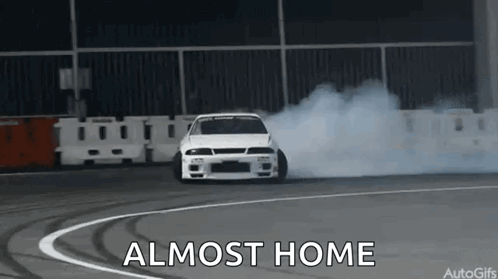 A White Car Is Drifting On A Track And The Words `` Almost Home '' Are Visible . GIF