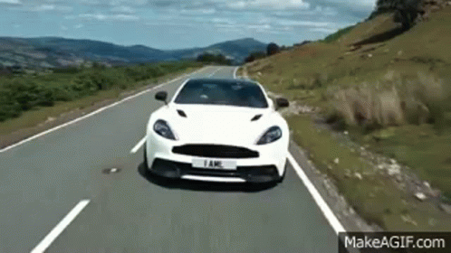 A White Car Is Driving Down A Country Road . GIF
