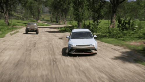 A White Car Is Driving Down A Dirt Road Next To A Brown Suv GIF