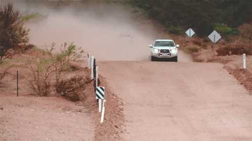 A White Car Is Driving Down A Dirt Road With A Sign That Says ' A ' On It GIF