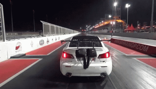 A White Car Is Driving Down A Race Track With A Bahraingp.com Sign Behind It GIF