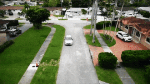 White Car Driving Down Residential Road GIF