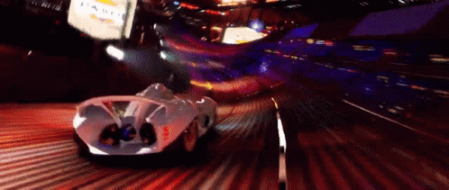 A White Car Is Driving Down A Road At Night With A Sign That Says Chevrolet In The Background GIF