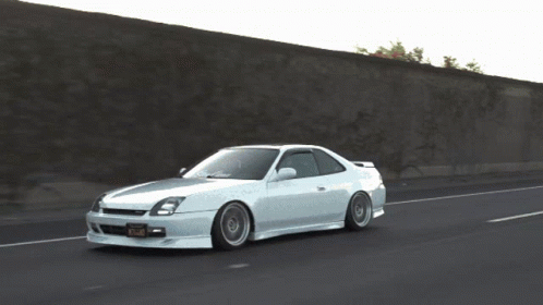A White Car Is Driving Down A Road With A California Tag GIF