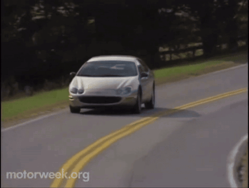 A White Car Is Driving Down A Road With Motorweek.org Written In The Corner GIF