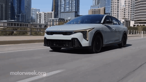 A White Car Is Driving On A Highway With Motorweek.org Written In The Corner GIF