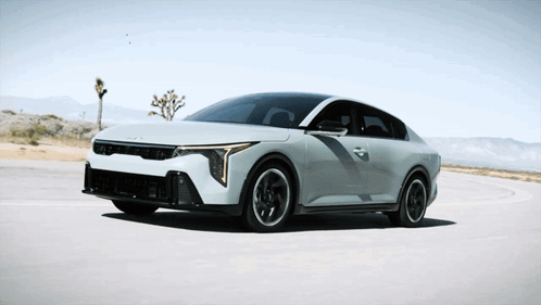 A White Car Is Driving On A Road With Mountains In The Background GIF
