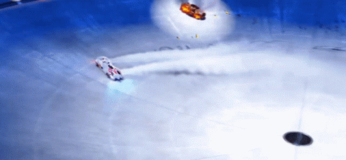 A White Car Is Driving On A Snowy Surface With A Red Car In The Background GIF