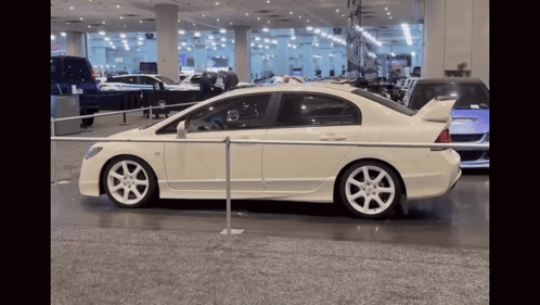 A White Car Is Parked Behind A Metal Barrier GIF