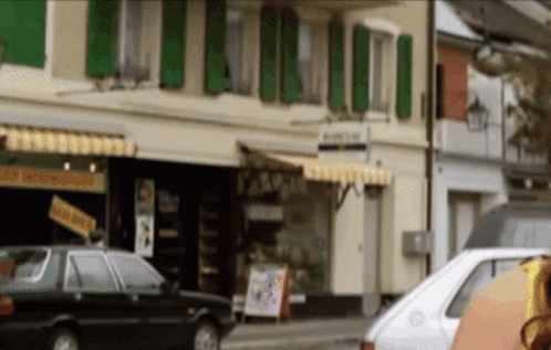 A White Car Is Parked In Front Of A Building That Has A Sign On It That Says ' A ' On It GIF