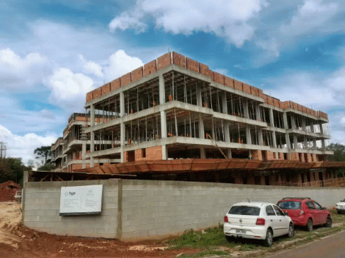 A White Car Is Parked In Front Of A Building Under Construction That Says Bgr GIF
