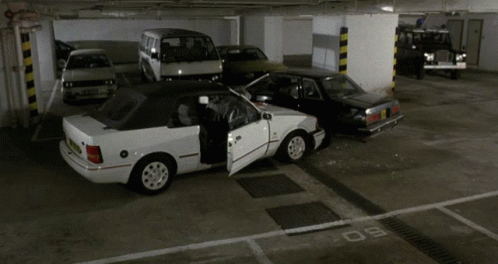 A White Car With The Door Open Is Parked In A Parking Lot GIF