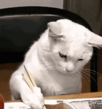 a white cat is sitting at a table with a pen in its paw