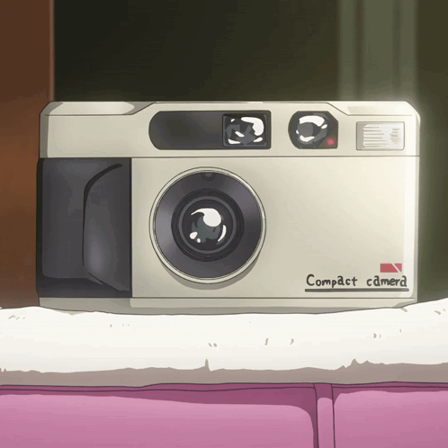 A White Compact Camera Is Sitting On A Pink Couch GIF