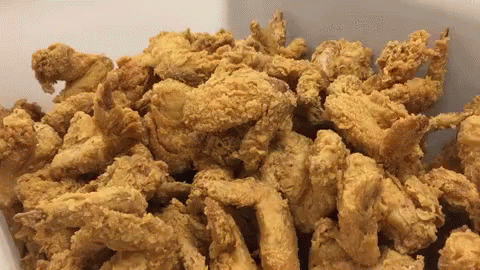 A White Container Filled With Fried Chicken Pieces GIF
