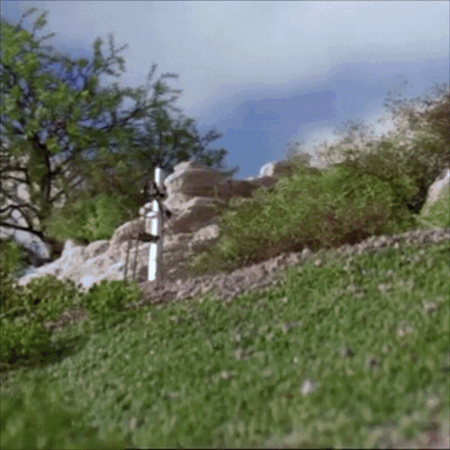 A White Cross In The Middle Of A Grassy Hill GIF